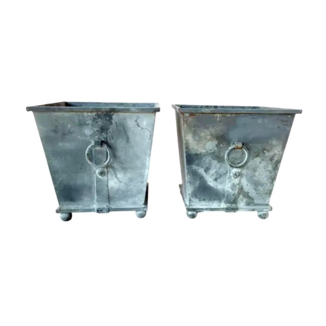 Pair of American Neoclassical Metal Planters. Crafted in a tapering square form, each planter features a weathered gray...