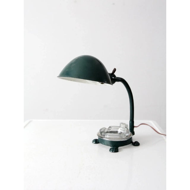 A 1930s Art Deco gooseneck desk lamp in green-painted metal, featuring a sculptural cast iron footed base, adjustable...