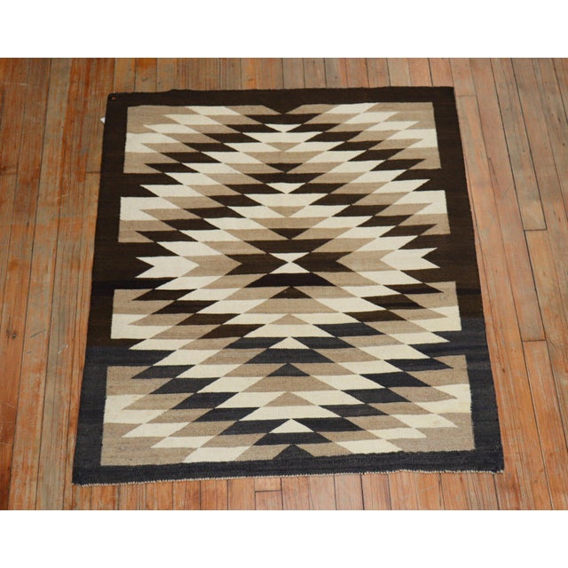 A highly decorative 20th century American Navajo rug with an all-over geometric tribal design in brown, charcoal, camel,...