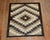 A highly decorative 20th century American Navajo rug with an all-over geometric tribal design in brown, charcoal, camel,...