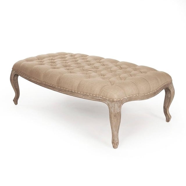 The Maison Tufted Ottoman from Zentique in natural burlap features an elongated oval shape with deep button tufting. The...