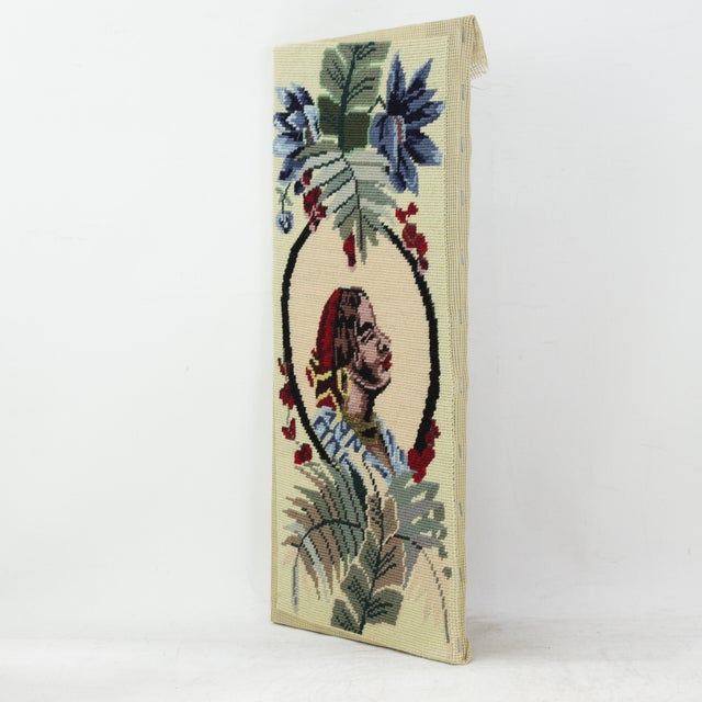 This vintage needlework panel features a striking profile portrait of a woman in a red headwrap and golden hoop earrings,...