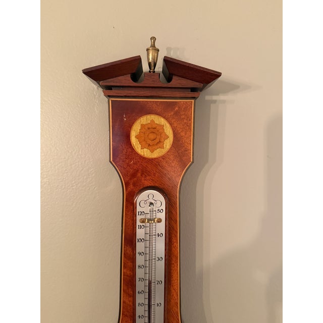 Comitti of London Sheraton style mahogany aneroid barometer with curl veneer, marquetry shell inlay and white/black...