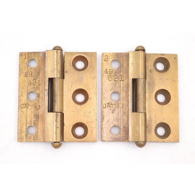 Vintage brass door hinges with button tips, three knuckles, and a template hole pattern. The original mounting screws are...