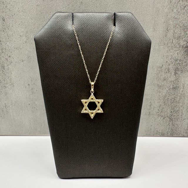 This Diamond Star of David necklace is crafted in 10kt yellow gold and features a meaningful Star of David pendant...