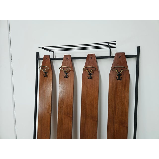 Vintage 1960s wall-mounted coat rack with a black lacquered iron frame supported by two height-adjustable brass feet. It...
