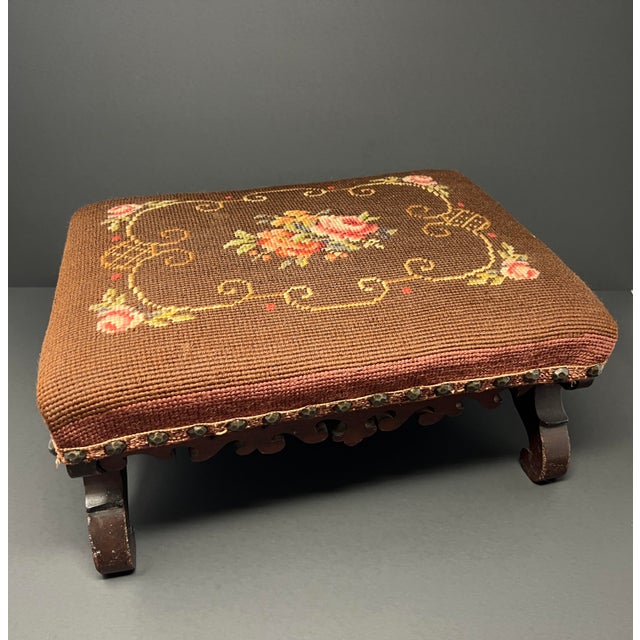A charming antique Victorian footstool featuring a beautifully carved hardwood base and hand-worked floral needlepoint...