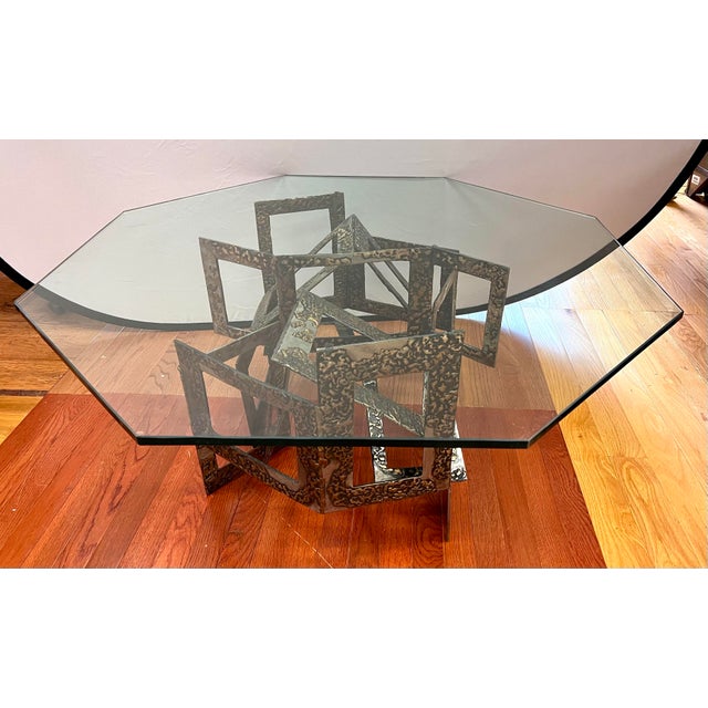 Brutalist sculptural coffee table with thick octagonal glass top and dramatic geometric metal base. A highly architectural...