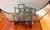 Brutalist sculptural coffee table with thick octagonal glass top and dramatic geometric metal base. A highly architectural...