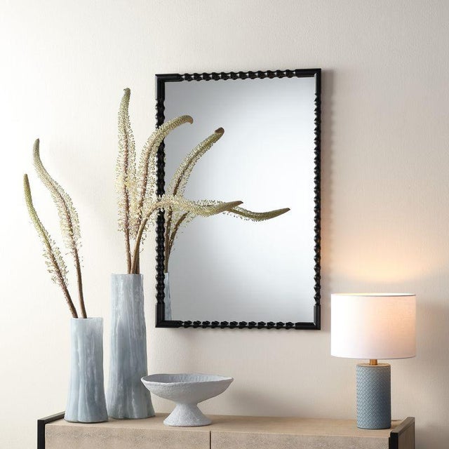 This striking yet understated wall mirror features a handwrought metal frame in a sleek black satin finish. Hang it...