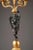 Stunning pair of gilded and patinated bronze candelabras, featuring a winged cupid. He is standing on a sphere and holding...