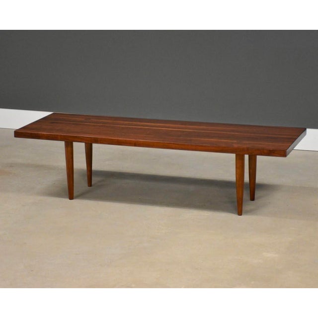 A mid century modern solid walnut coffee table with round wedged mortise and tenon legs. Made in USA. Professionally...