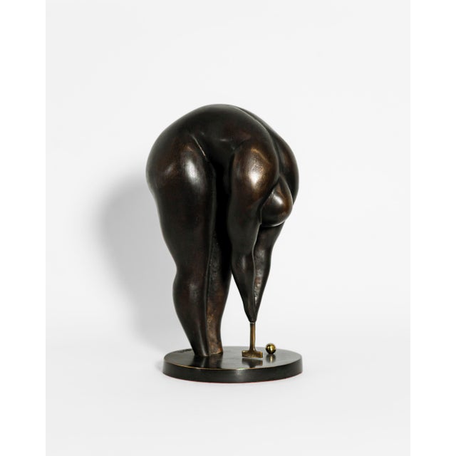 A contemporary figurative bronze of a woman bent low over her croquet mallet, her body folded at the waist into one...