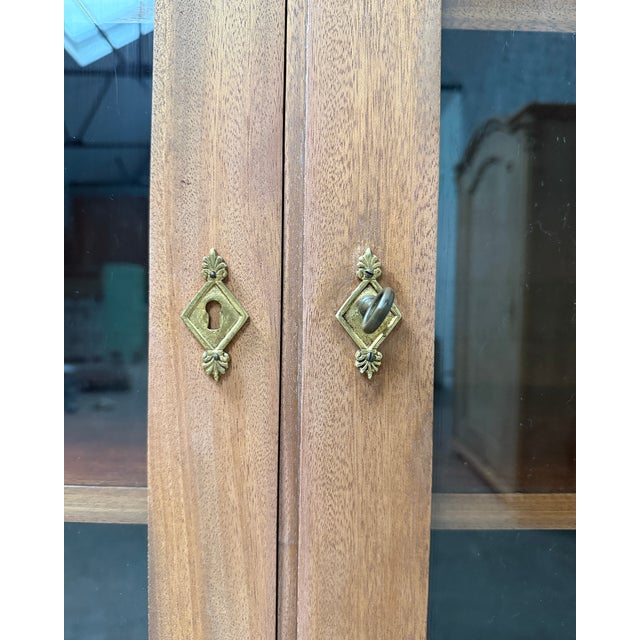 This elegant empire-style display cabinet, dating from the 1950s, captivates with its balanced lines and striking...