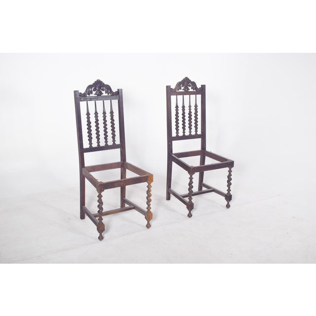 Pair of turned chairs. In dark wood with a high back, richly decorated with floral carvings on the top and turned spikes...