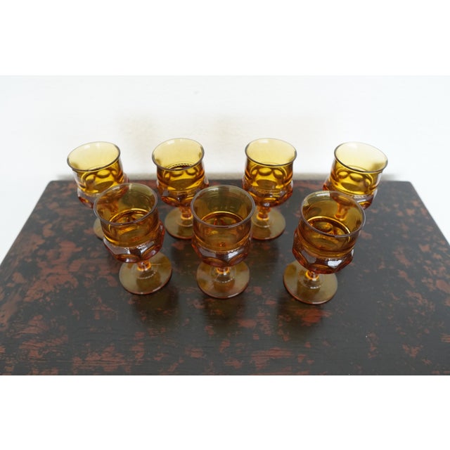This vintage set of seven amber glass goblets by Indiana Glass features the iconic King’s Crown (Thumbprint) pattern, a...