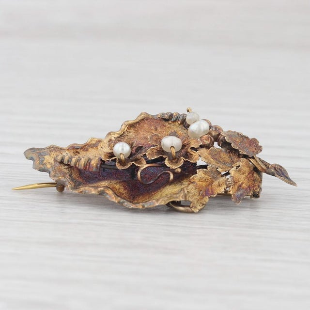 This lovely antique brooch features finely detailed floral work along the body of a leaf design. This piece comes with an...