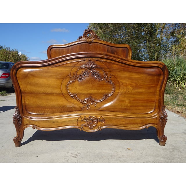 A very old, handcrafted bed, dating from the late 19th or early 20th century, made of solid walnut, with rounded curves...