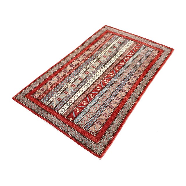 Rich jewel tones and intricate linear patterns define this hand-knotted small area rug. Inspired by traditional Persian...