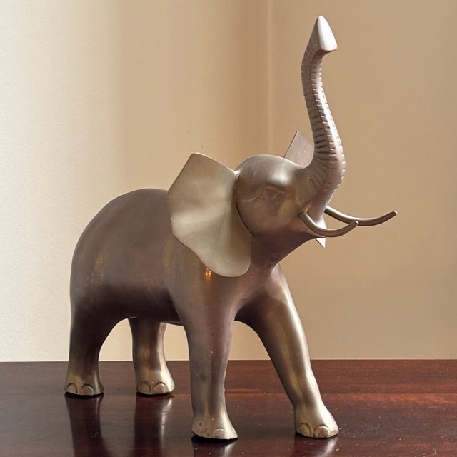 Offering gorgeous mid-20th century brass elephant sculpture with lovely aged patina. With long trunk pointed upwards, this...