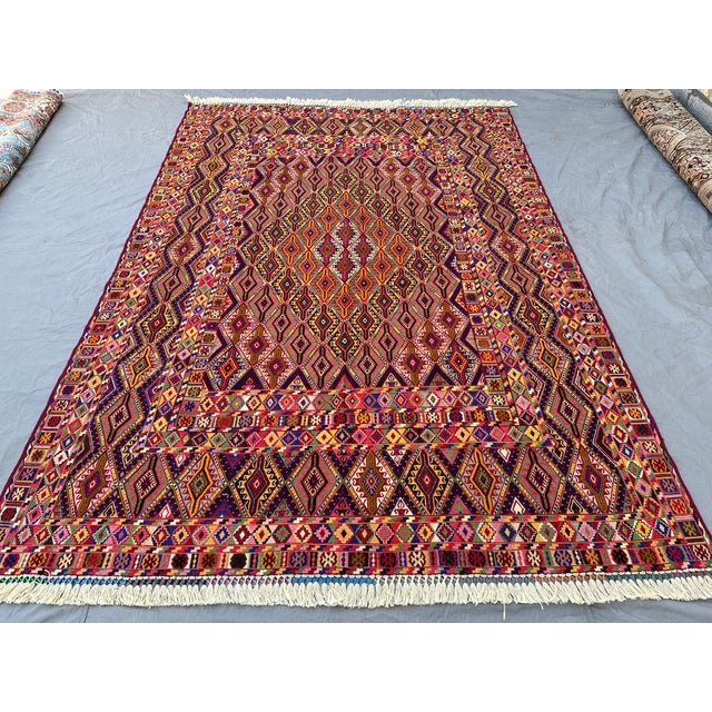 This vibrant Mushwani Maimana kilim features a dense allover lattice of serrated diamonds in a rich, varied palette of...