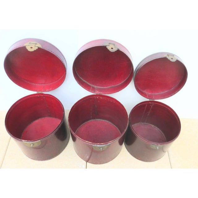 Set of three leather cylinder storage trunks. Chinese deco designs with oxblood deep maroon polished leather and Chinese...