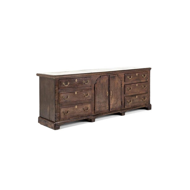 A splendid george iii oak dresser base with a slightly oversailing two plank top with walnut banding. The richly patinated...