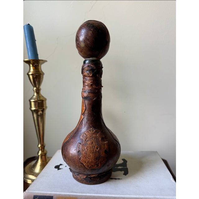 An authentic vintage mid-century Italian decanter wrapped in rich, hand-tooled leather featuring an embossed Fleur-de-Lis...