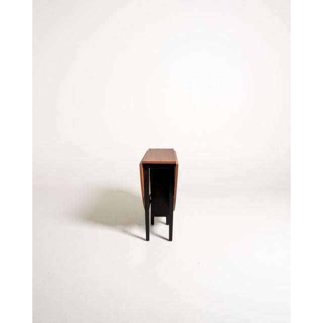 Folding teak table with two independently lifting wings and a black lacquered wooden frame. Made in Sweden, 1960s. Swedish...