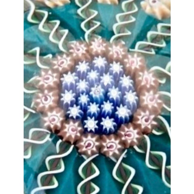A gorgeous, vintage art glass paperweight. Features an open “wagon wheel” style design with 15 ribbon twists radiating...