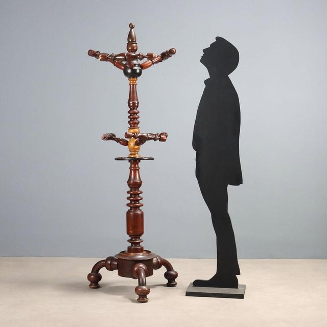 Coat stand in elm, maple, and ebonized parts. Three upper and three lower hangers, three umbrella stands, central shaft...