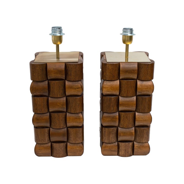 A striking pair of sculptural table lamps crafted from solid teak wood, featuring its characteristic warm brown tones and...