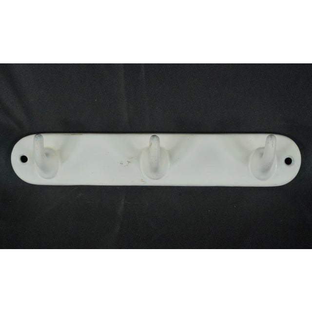Vintage European wall rack with three single arm hooks made of cast iron with a white enamel finish. The original mounting...