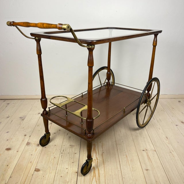 Mid-Century wood bar cart trolley made in Italy in the 1970s. Dark brown wood, glass. Good vintage condition. Dimensions:...