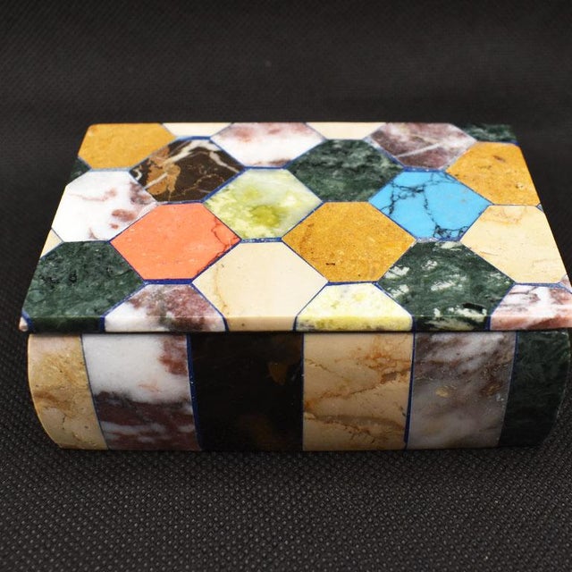 A beautiful colorful decorative box with a lid created from Carrara marble and inlaid with a variety of semi-precious...