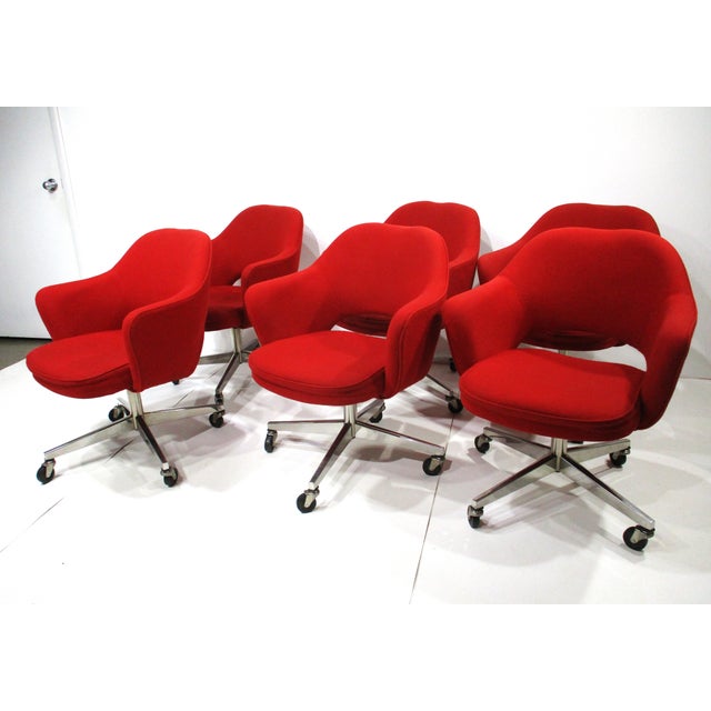A set of stunning vintage red upholstered swiveling armchairs with polished chrome steel four star rolling bases on black...