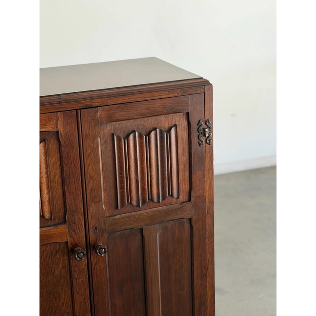 W34 D17 H48 This vintage oak armoire features carved panel doors with geometric detailing, original hardware, and a warm...