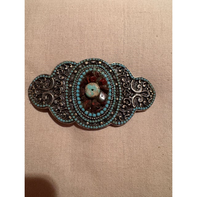 This vintage heavy silver belt buckle features intricate detailing with turquoise and inset stones, showcasing a Native...