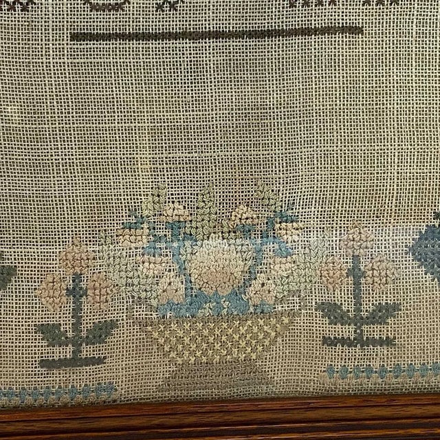 DETAILS An antique framed, rectangular needlework sampler with four rows of block alphabets in upper and lower case and...