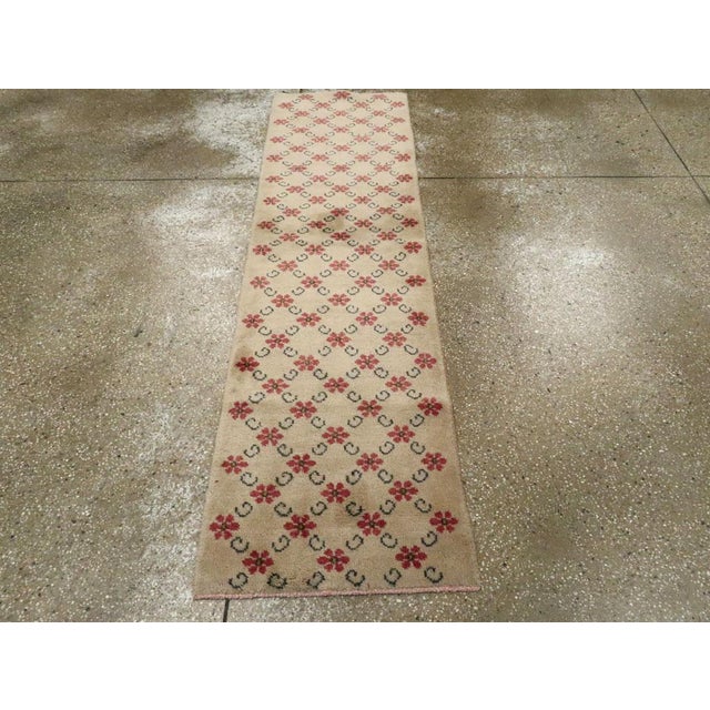 This mid-20th century Turkish Anatolian runner, measuring 1' 10" x 6' 8", showcases a charming and delicate floral lattice...
