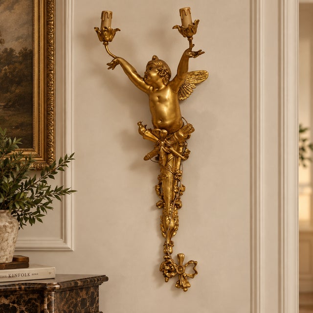 Add dramatic French elegance to your walls with this ornate Rococo-style cherub wall sconce, featuring a sculptural winged...