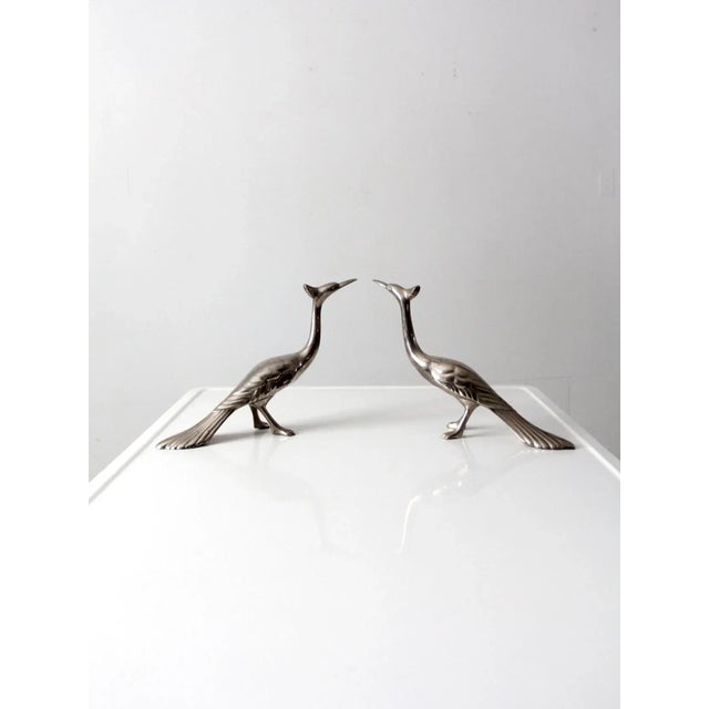 This is a pair of mid-century peacock figurines. Graceful lines shape the silver tone metal birds with beautiful detailing.