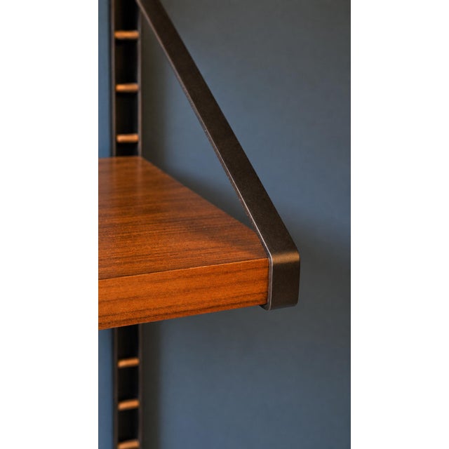 Vintage modular wall-mounted bookcase, dating back to the 1960s, made of striped mahogany with a burnished metal frame and...