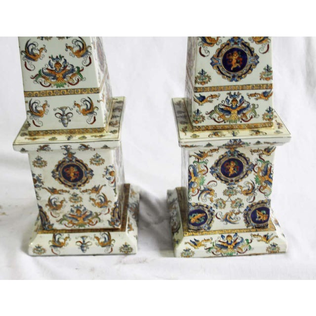 Pair of highly decorative, hand painted porcelain obelisks. Wonderful vibrant color decoration with cherubs on plaques. H...