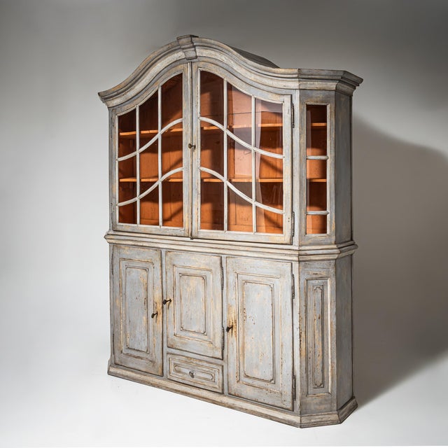 Two-part kitchen cupboard with a glazed upper section and a closed lower cabinet. The shaped cornice and finely divided...