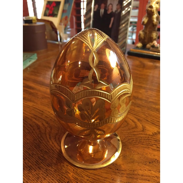 This blown glass egg on stand is a AMBER/YELLOW color with intricate etched decorative designs. The gold colored floral...
