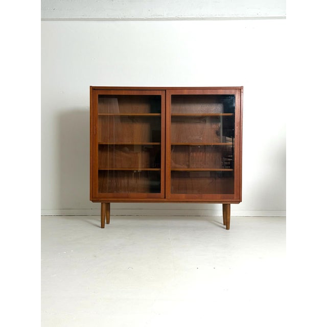 Teak Display Cabinet with Sliding Doors, 1960s A stylish Danish teak display cabinet from the 1960s. The clean lines and...