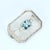 This brooch features a central aquamarine stone, cut in a mixed style, displaying a captivating blue hue. Flanking the...