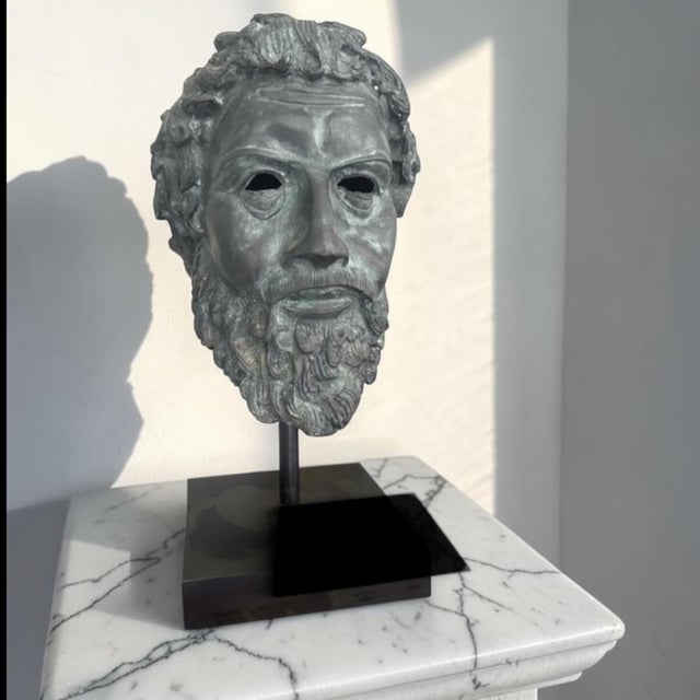 A striking classical head sculpture cast in bronze and finished with a richly layered verdigris patina. The fragmentary...