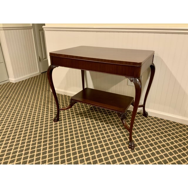 A vintage two-tier mahogany accent side table in a warm reddish-brown finish with visible grain figuring with a...